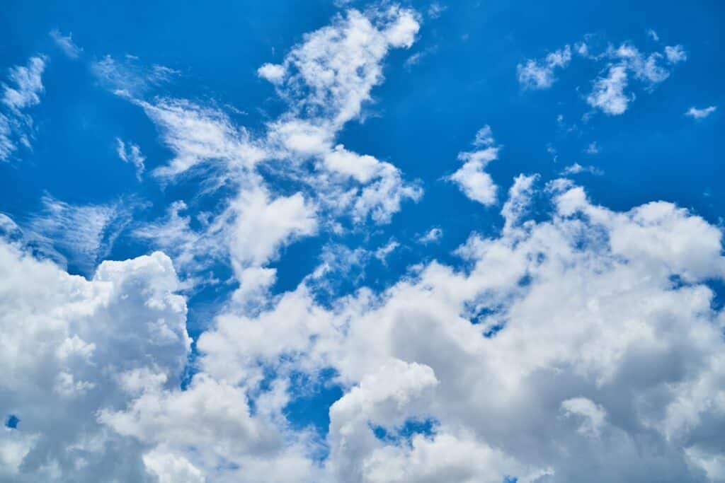 White clouds being blown away to reveal clear blue sky